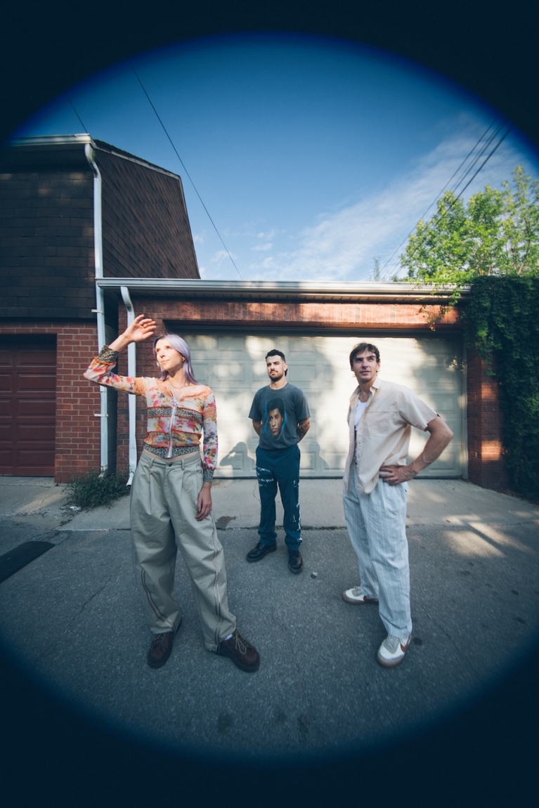 Devan, Khalid, and Andrew stand in a driveway. 