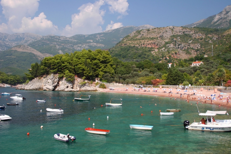 Boten liggen in groenblauw water langs een weelderige kustlijn in Bar, Montenegro