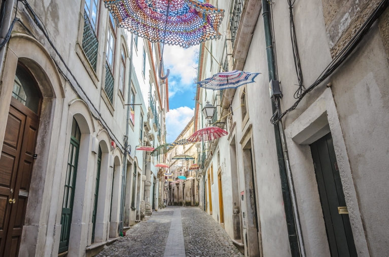 Schirme hängen in einer engen Gasse in Coimbra