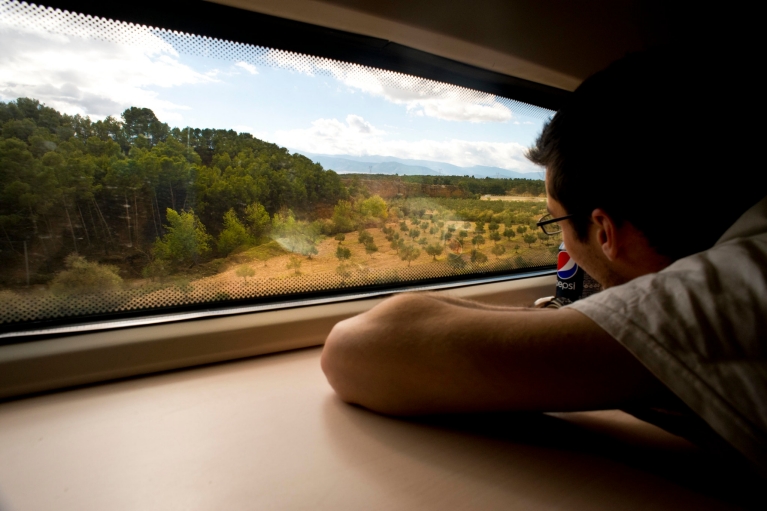 Hombre mirando el paisaje desde la ventana de un tren AVE, Almería - Granada, España
