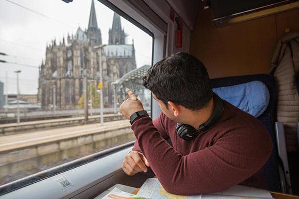 young_man_looking_at_cologne_cathedral_from_a_train_window_in_germany