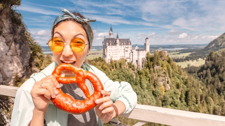 germany-neuschwanstein-castle-background-woman-eating-pretzel