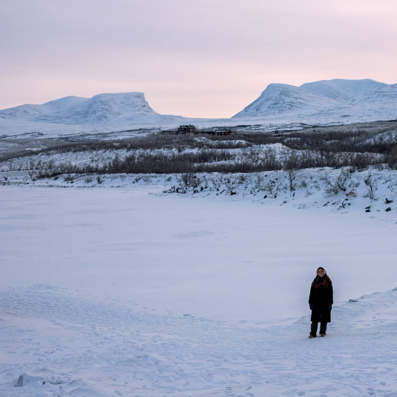 Person am Ufer eines zugefrorenen Sees in Abisko, Schweden