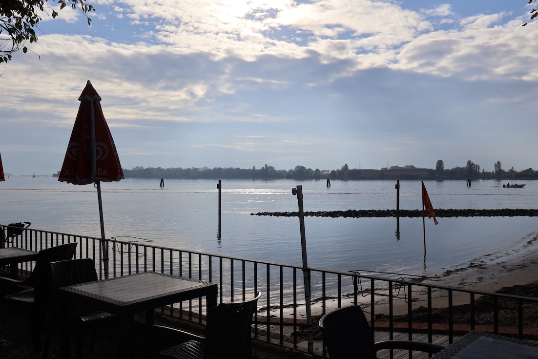 A beach on the Venice lagoon, with picnic tables in the foreground