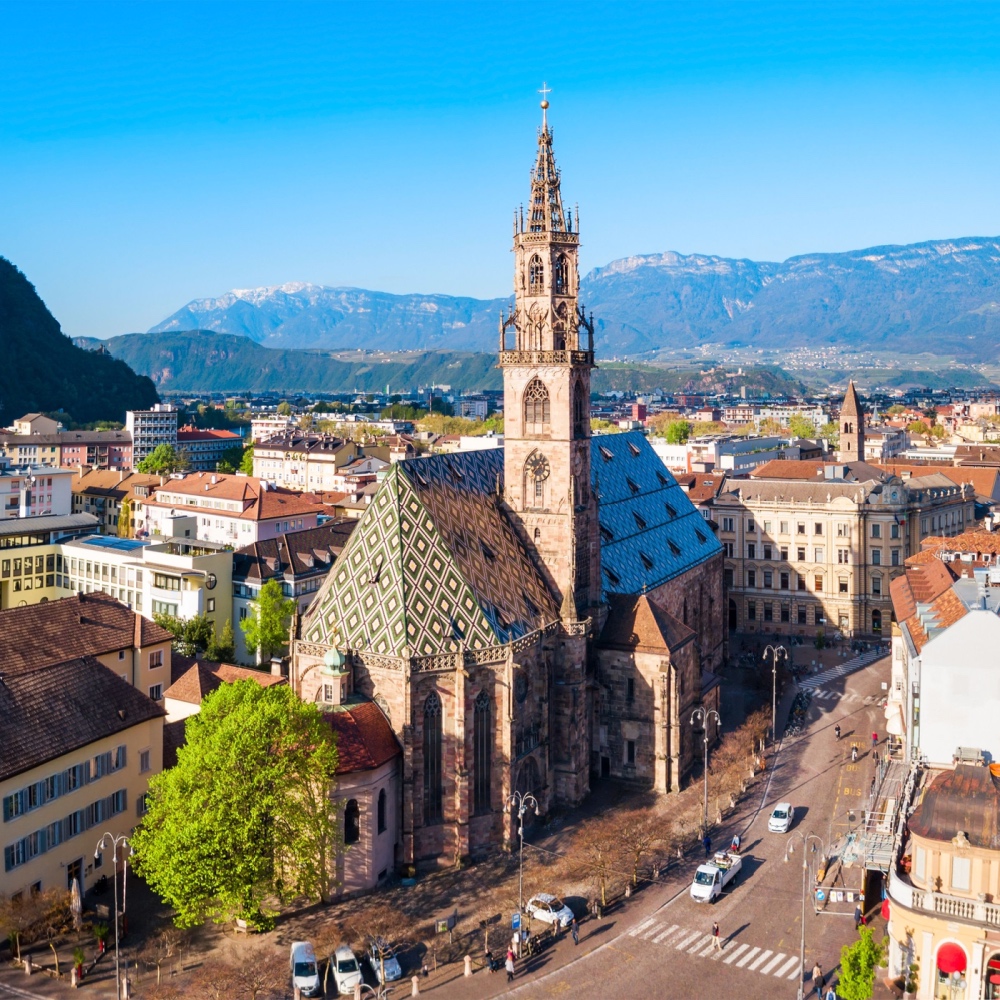 Una veduta aerea della cattedrale di Bolzano, con palazzi e montagne sullo sfondo